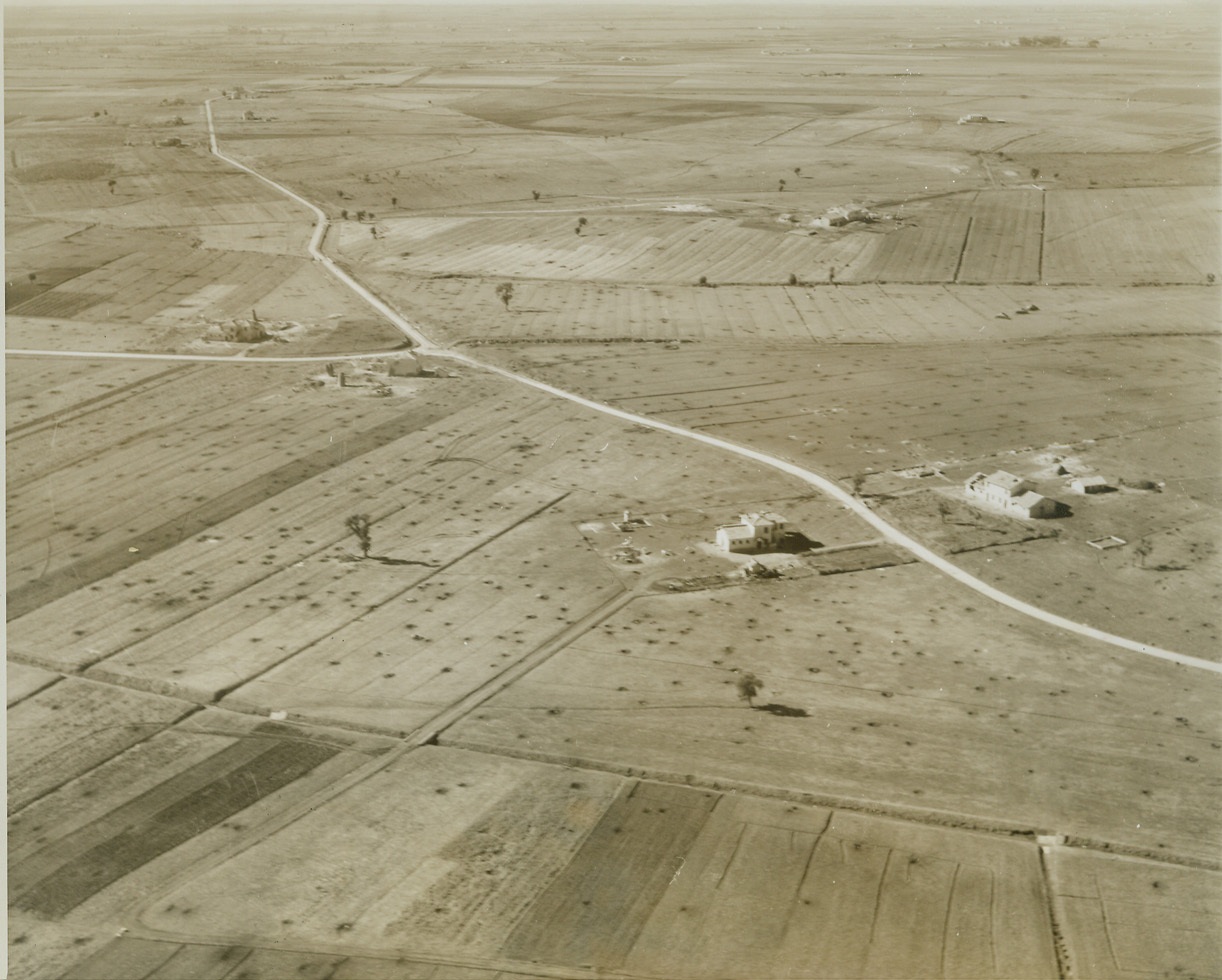 Germans Fire on Allied Positions, 5/22/1944. Cisterno Area, Italy – The flat terrain, scene of front line fighting between the Anzio beachhead forces and Nazi troops, is pockmarked with shell holes and bomb craters. The Allied beachhead forces are moving rapidly forward to join the 5th Army troops, which today (May 22) moved into Terracina, only 24 miles form the beachhead positions. Should this junction be effected, Nazi forces falling back toward Rome would be imperiled by the Allies advancing toward that key city. Credit (ACME Photo by Charles Seawood, War Pool Correspondent);