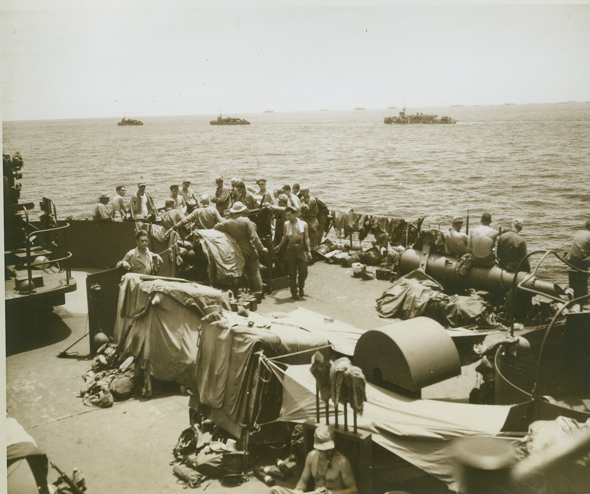 PART OF HOLLANDIA INVASION FLEET, 5/3/1944. DUTCH NEW GUINEA – As far as the eye can see, craft of the huge Allied invasion fleet which Hollandia, Aitape, and Tanamerah Bay, dot the surface of the sea as they head for the Dutch New Guinea coast. In the foreground, men aboard one of the ships relax in the warm sun, enjoying the last few moments before the attack. (Passed by censors.) Credit: ACME photo by Thomas L. Shafer for the War Picture Pool;