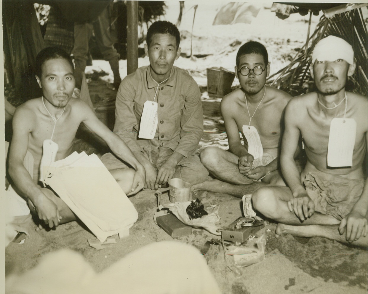 GLAD TO SAMPLE YANK RATIONS, 5/3/1944. DUTCH NEW GUINEA – Jap prisoners, captured during the Allied attack on Aitape, Dutch New Guinea, part of the Hollandia invasions, squat around U.S. field rations which they enjoy in spite of the fact that they wanted to be killed during the attack. (Passed by censors.) Credit: ACME photo by Thomas L. Shafer for the War Picture Pool;