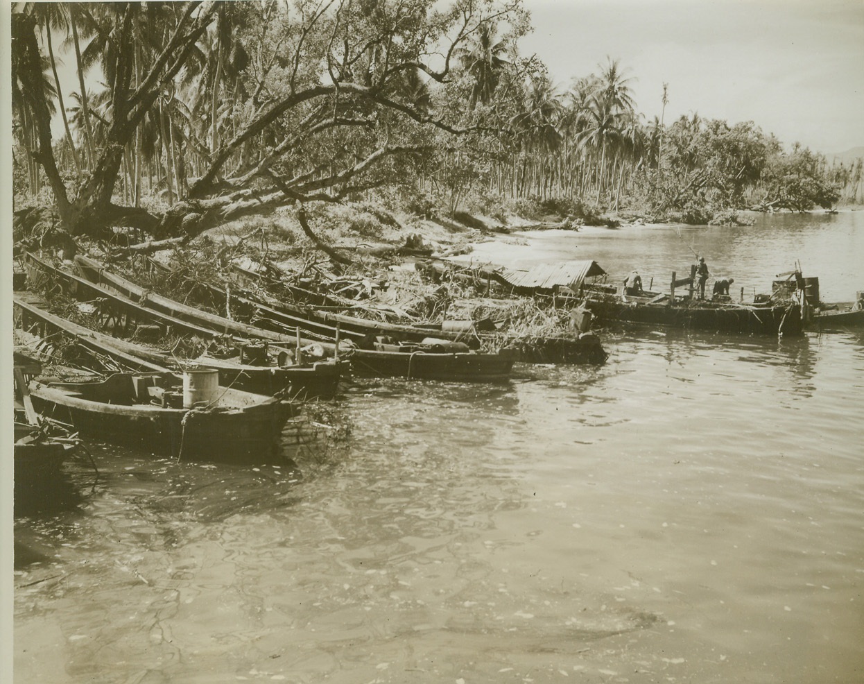 JAP BARGES BURNED OUT BY BOMBARDMENT, 5/3/1944. DUTCH NEW GUINEA – U.S. troops (right) look over Jap barges on Selso Island, burned out under shelling by Allied warships. The island is one of three in Aitape Harbor attacked during the invasions of Dutch New Guinea. (Passed by censors.) Credit: ACME photo by Thomas L. Shafer for the War Picture Pool;