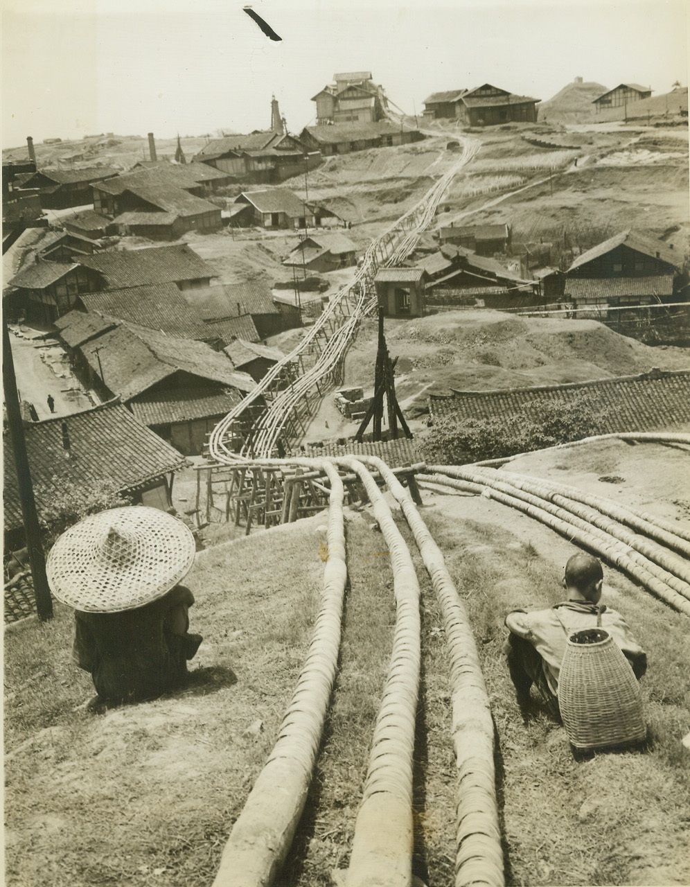 SALT FOR THE CELLARS OF CHINA, 5/23/1944. TSE LIU CHING, CHINA – One of the most thriving industries in this area of China is the salt mines located at Tse Liu Ching. These mines, 2,600 years old, are cultivated by rustic methods, but nevertheless produce 250,000 metric tons of salt a year, or one fourth of all the salt produced in free China. Three hundred thousand laborers work the mines, from which salt is shipped to all parts of the East. Picture shows bamboo pipelines running toward one of the refineries from the wells. Credit: ACME photo by Frank Cancellare, War Pool Correspondent;
