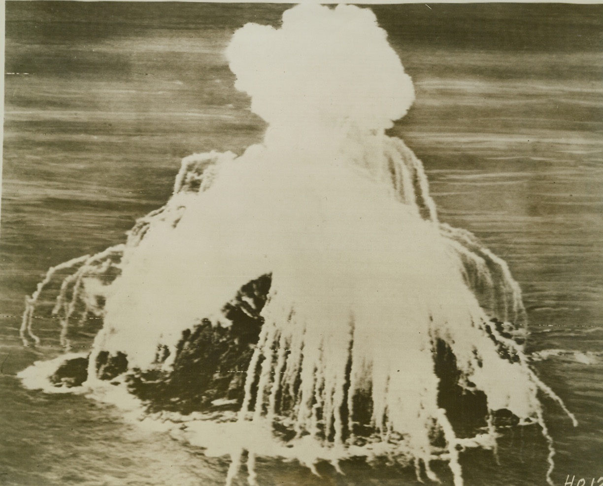 INCENDIARY “SHOWER” FOR JAPS, 5/2/1944. This photo, flashed from Hawaii to the U.S. by radiotelephoto, shows a white phosphorous bomb “shower” from planes of the U.S. Seventh Air Force completely enveloping a small unidentified Jap-occupied island in the central Pacific area. (Note background has been blanked out for security reasons.) Credit: Army radiotelephoto from ACME;