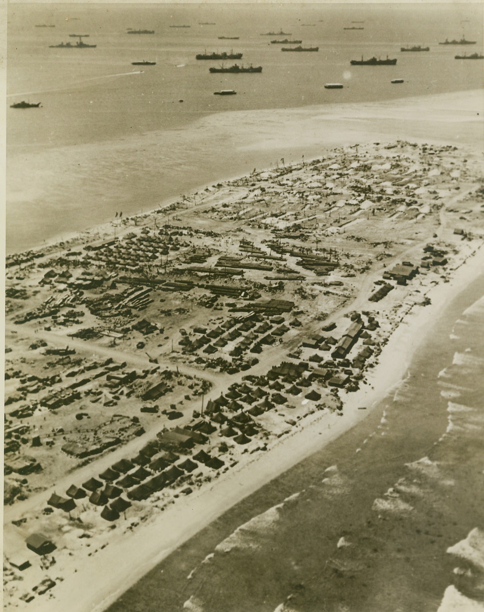 YANKS REBUILD KWAJALEIN, 5/2/1944. KWAJALEIN – This aerial view of newly-conquered Kwajalein Island in the heart of the Marshalls Group shows how the U.S. Navy Task Force is at work rebuilding the shell-shattered base. Rows of tents house Seabees, whose skillful efforts have already partly removed the pock-marks of war on the Atoll. Part of the Navy Task Force can be seen anchored offshore. Credit: U.S. Navy photo via OWI Radiophoto from ACME;