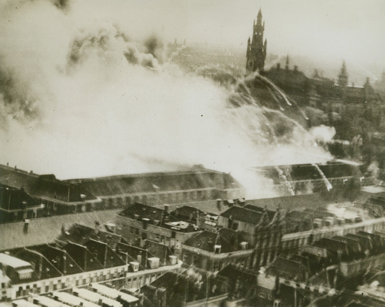 MOSQUITOES BOMB THE HAGUE, 5/9/1944. By pinpointing, attacking and destroying one particular building in the Hague, RAF Mosquitoes of the 2nd Tactical Air Force carried out one of the most spectacular attacks of this war. Many valuable German records were destroyed as a result of the raid. Here is a view of the attack, as the target area is enveloped in the smoke from bombs dropped by our aircraft. In background is the tower of the Peace Palace. Credit: British official photo from Acme;