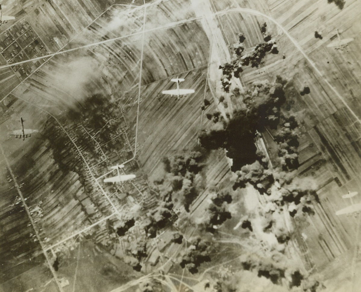 Ploesti Smashed Again by U.S. Airmen, 5/6/1944. PLOESTI, ROMANIA—Stepping up their non-stop pace in air offense, the Allies again hit the railroad marshalling yards at Ploesti and here Allied bombers wing over their target, leaving explosions and fires in their wake. The Flying Forts, based in Italy, were playing an early return engagement on the oil center which they attacked heavily not long ago. It appears that the Allies’ aim is to cripple German transportation and supply facilities as much as possible before the dawn of “D” day.  Credit: OFFICIAL AAF PHOTO FROM ACME.;
