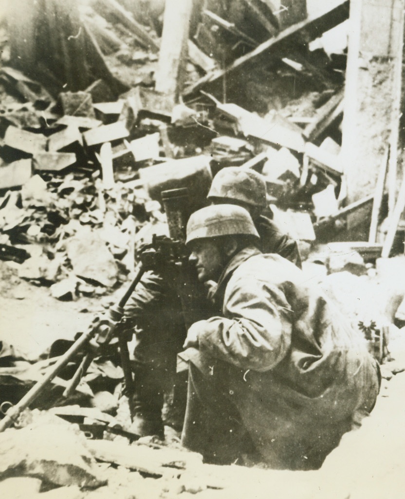 Nazi Paratroopers “Gunning” in Italian streets, 5/5/1944. CASSINO, ITALY—The caption accompanying this German photo, received in  the U.S. through Sweden and London, describes it as showing German paratroopers manning a mortar gun during street fighting in the Cassino convent area. Note the ruined buildings which completely surround the gun nest.  Credit: ACME.;