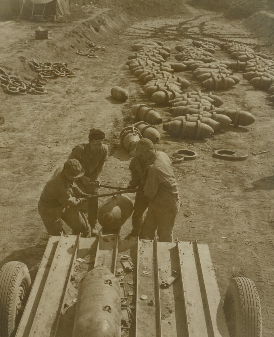 Headed for Hitlerland, 5/11/1944. ITALY—The work of the Air Force Service Groups often go unheralded but they keep Allied aircraft in the air and hitting at the enemy. Nobody, however, appreciates their service more than the men who fly the planes they repair and sometimes maintain. Here, at an USAAF base in Italy, bombs are started on their journey of destruction aimed at Hitler.  Credit: ACME photo by Charles Seawood, War Pool Correspondent.;