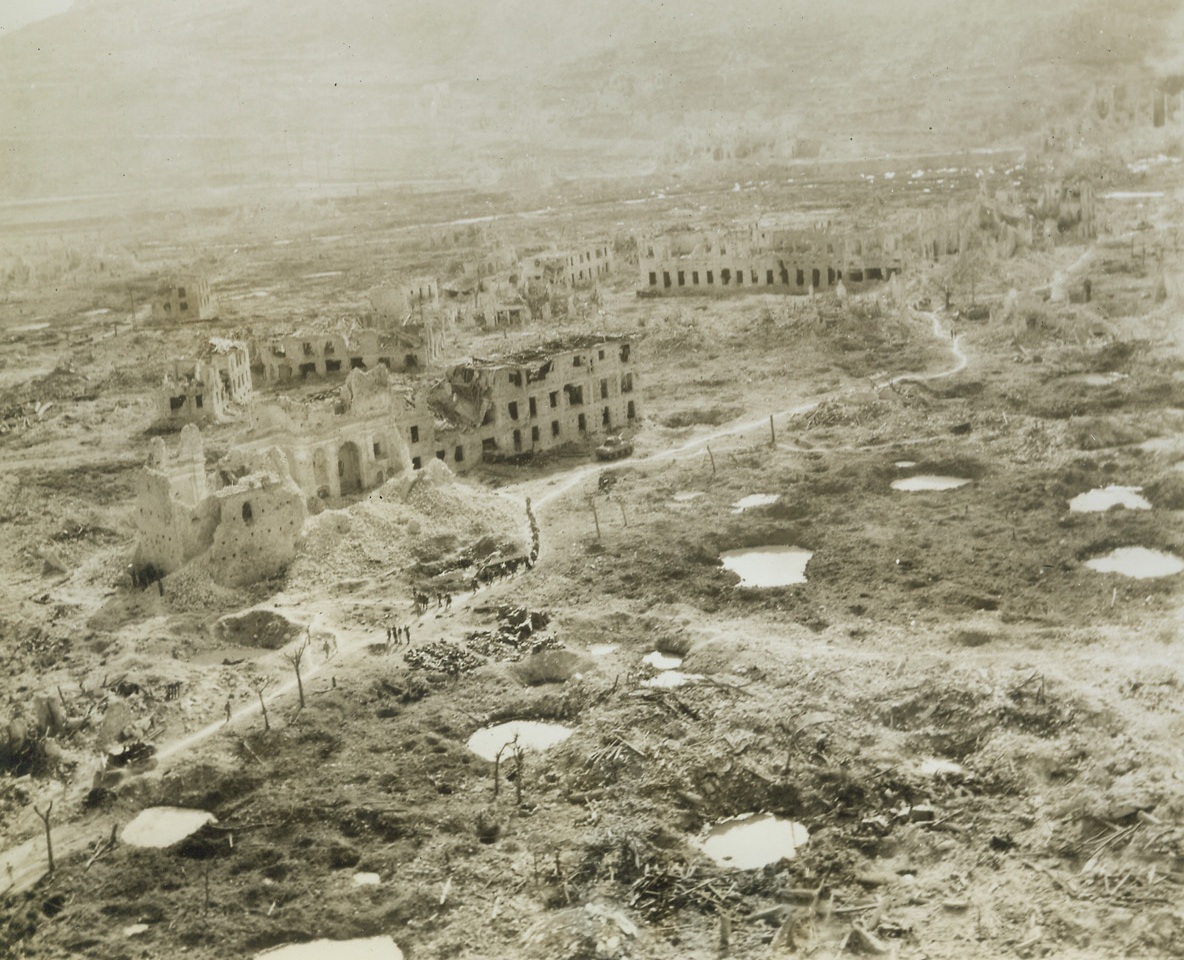 Ghost Town,  5/24/1944. CASSINO, ITALY—Here’s the entrance to Cassino from Route 6. The first building at the left in a bombed-out, while others are not identifiable. Only broken walls remain after virtually a four-month siege during which time countless rounds of artillery fire were poured into the town and thousands of tons of bombs were dropped on the German stronghold of the Gustav Line. Credit: ACME photo by Charles Seawood, War Pool Correspondent.;