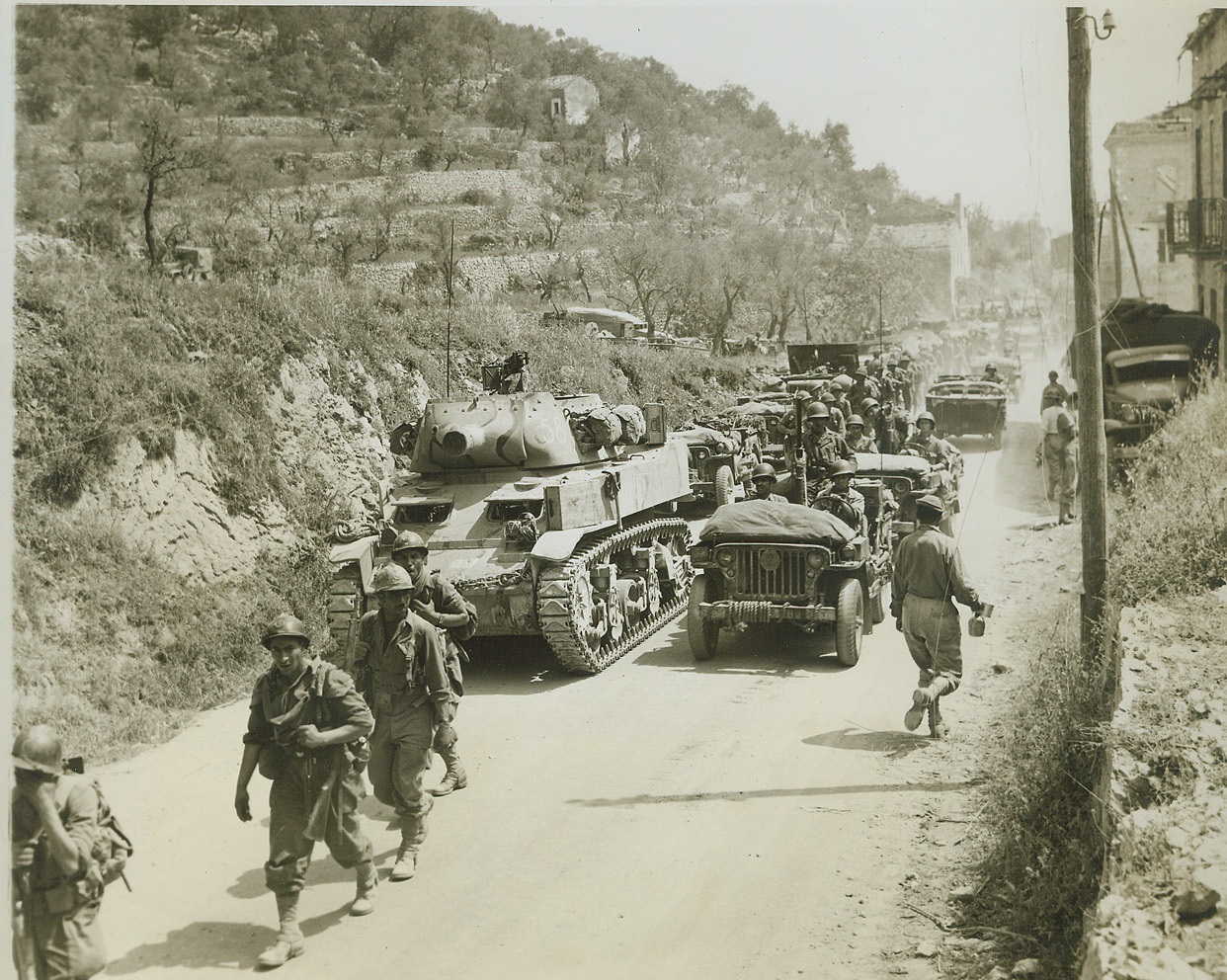One-Way Traffic – to the Front, 5/23/1944. Esperia, Italy – French infantrymen of the Allied Fifth Army, (left, foreground), march along a road toward Esperia ahead of a long line of Fifth Army vehicles, after the Allies had smashed through the Gustav Line in Italy. Today, Americans on the Anzio beachhead began a smashing offensive synchronized with a renewed attack on the Hitler Line by troops of the Fifth and Eighth Armies.  Credit: (ACME Photo by Charles Seawood for the War Picture Pool);