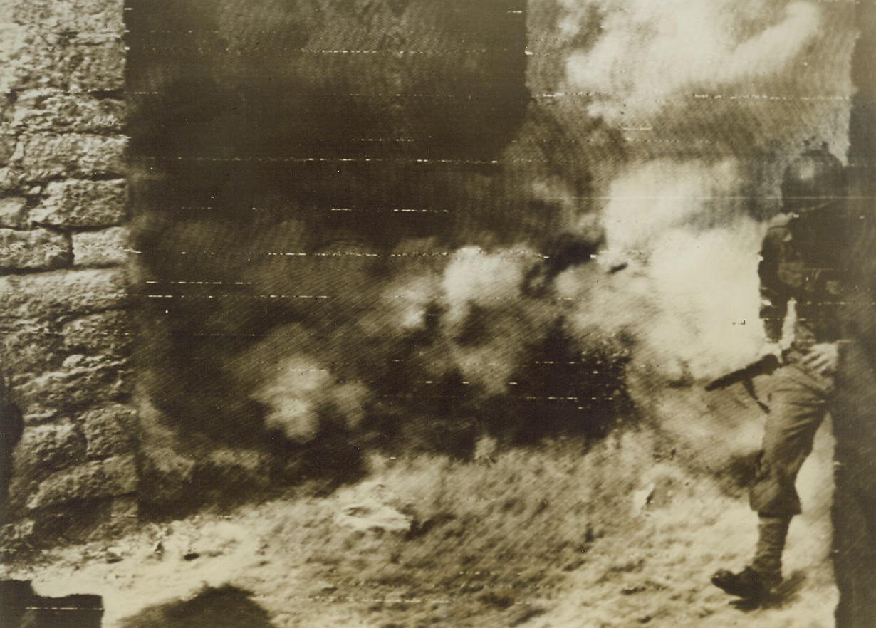 Rounding Corner to Trouble, 5/1/1944. ITALY—Rounding a corner in a narrow street of an Italian village while on daylight patrol, this American soldier runs into enemy mortar fire. The Yank was wounded by the shell exploding in the dust before he could take cover. Credit: U.S. ARMY RADIOTELEPHOTO FROM ACME.;