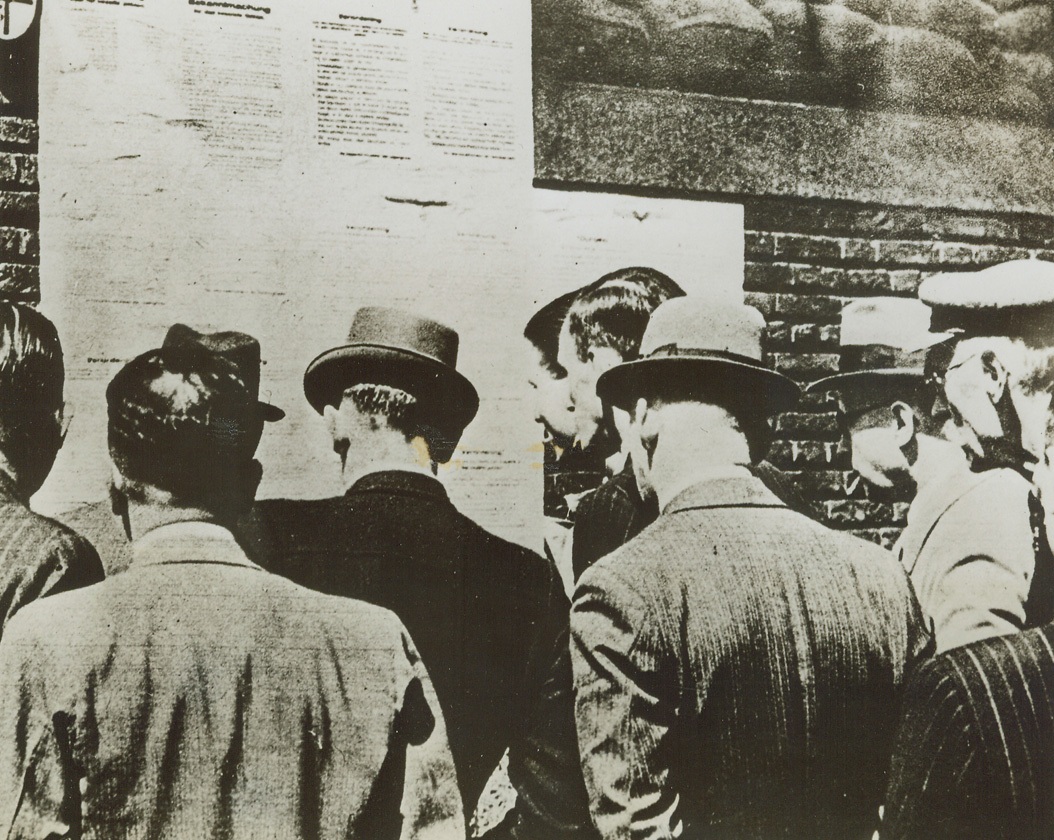 Holland Tense as “D” Day Nears, 5/26/1944. HOLLAND—Their expressions unreadable, these Dutch-men in occupied Holland flock to read the Latest Nazi decrees. This photo, just received from England, is a good example of the prevailing tenseness in Western Europe as “D” day, and the day of their liberation nears. Credit: ACME.;