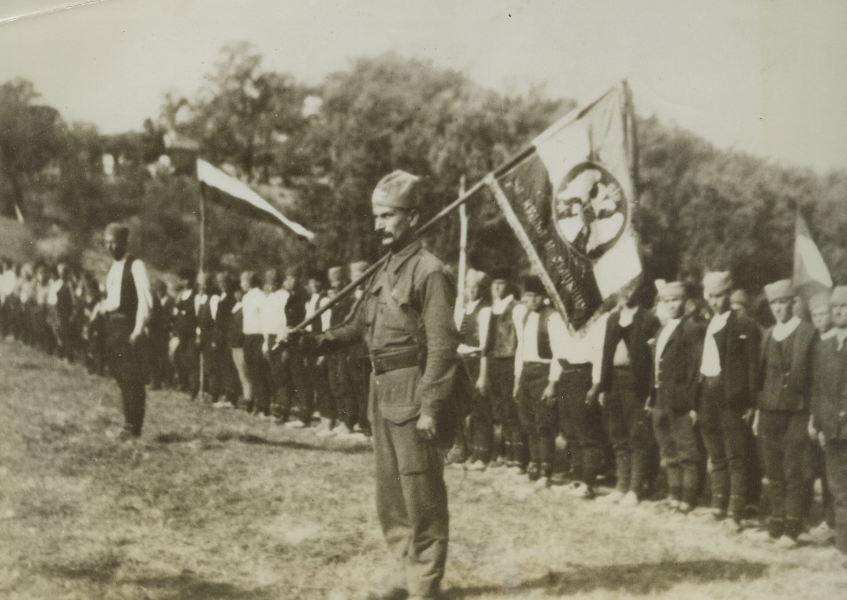 Mikhailovich Recruits, 5/2/1944. YUGOSLAVIA—New recruits of the Kings Mountain Guards stand at attention in the hills of Serbia awaiting orders, the flag in the foreground was made by nuns of a monastery in Serbia. This is but one of the many divisions fighting under guerrilla leader Draja Mikhailovich. A Mikhailovich aide arms and supplies 400,000 effectives could be mobilized. Credit: ACME.;