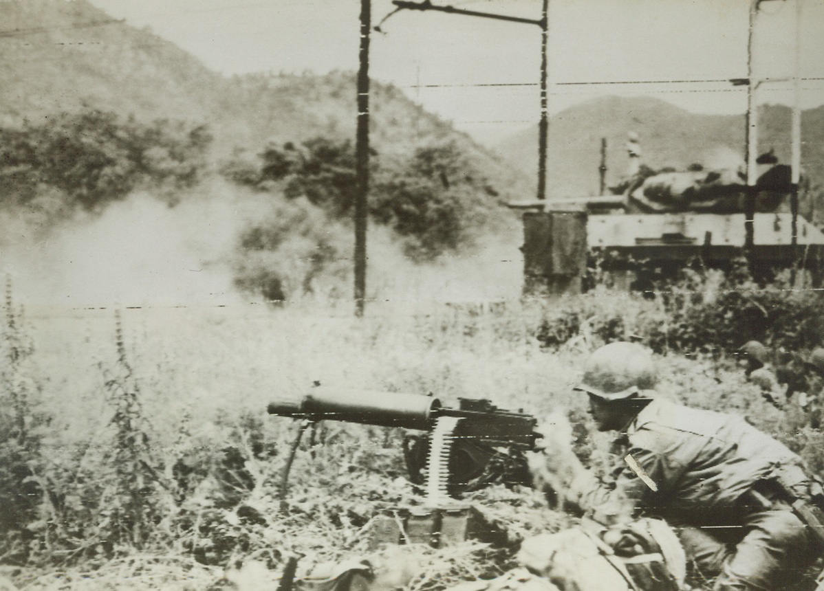 BOTTLING UP THE GERMANS, 5/25/1944. FONDI, ITALY—A M-10 tank destroyer of the American forces fighting with the Allied Fifth Army near Fondi, slams heavy shells into the Mont Orso Tunnel along the west coast electric rail line where Germans were trapped by the Yanks. An American machine gunner, (foreground), helps to blast the enemy out of their hole. Today, American forces driving south from the Anzio beachhead formed a juncture with other U.S. troops heading north from captured Terracina, at Lake Fogliano. Credit: Army Radiotelephoto from Acme;
