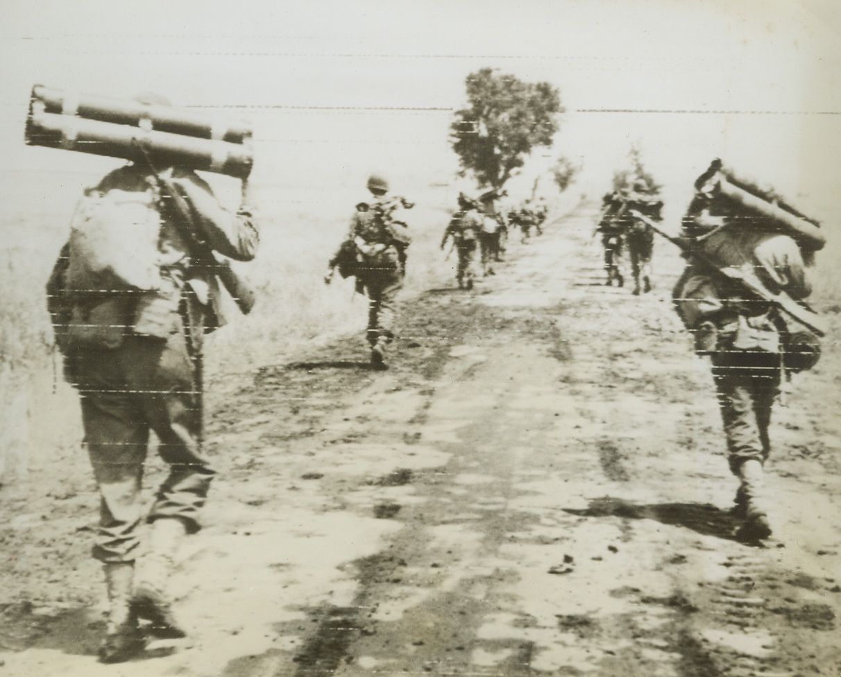 HEADED FOR ROME—WITH A VENGEANCE, 5/25/1944. CISTERNA, ITALY—An American Fifth Army mortar platoon advances in open order, to support troops smashing toward Rome from captured Cisterna in the renewed Anzio beachhead offensive. Today, Anzio forces and Yanks moving north from Terracina, met near Lake Fogliano joining the two fronts. Credit: Army Radiotelephoto from Acme;