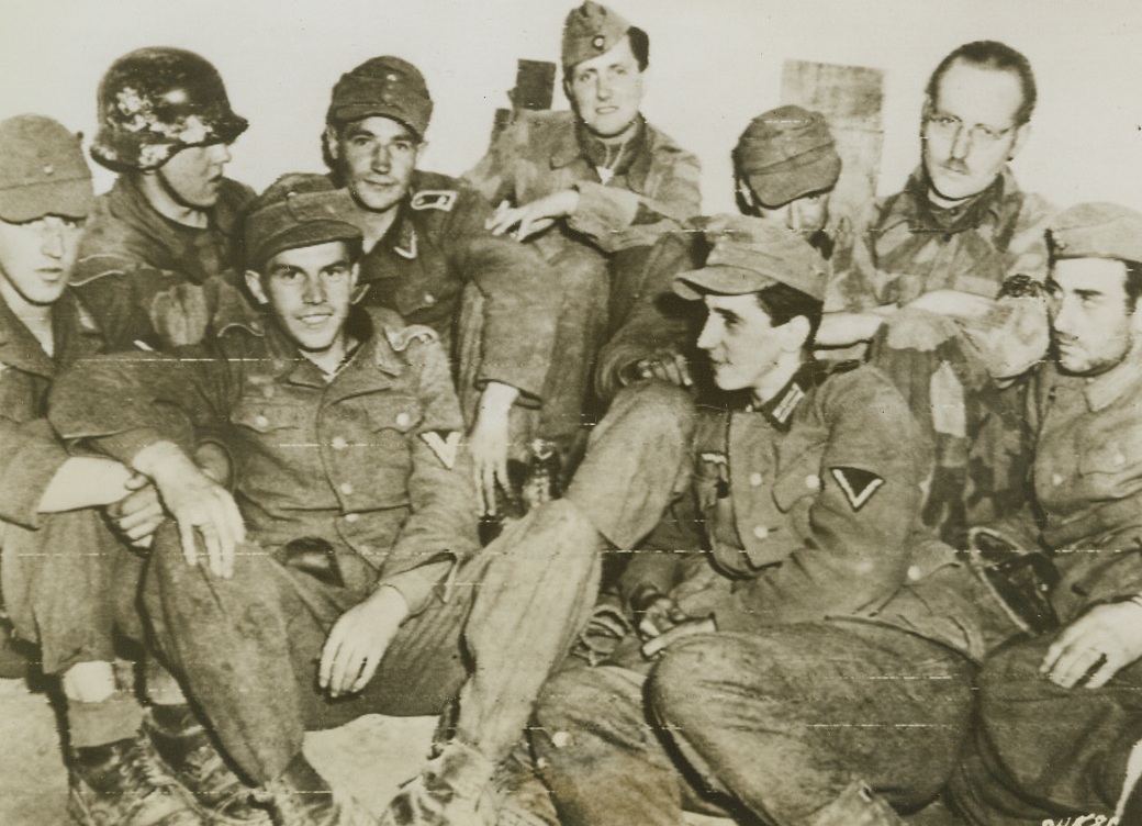 MORE GERMAN PW IN ITALY, 5/26/1944. ITALY—German prisoners of war, captured during the first day’s battle in the new Italian offensive, relax before being marched to the rear and PW compounds. Note German medical man (right) in camouflaged battle dress. Credit: Signal Corps Radiotelephoto from Acme;