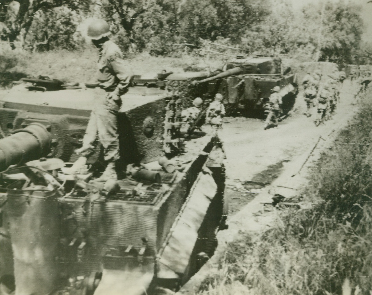 ABANDONED IN FLIGHT, 5/30/1944. CORI, ITALY—Yank infantrymen, advancing into Cori after the German evacuation, pause on the road to examine two knocked out Nazi “Tiger” tanks. Fleeing desperately with the Allies on their heels, the enemy forces left behind volumes of equipment in all stages of disrepair. Allied armies have continued their advance toward Rome, and latest reports state that at least three drives have cut into Nazi defenses in the Alban Hills sector. Credit: Signal Corps Radiotelephoto from Acme;