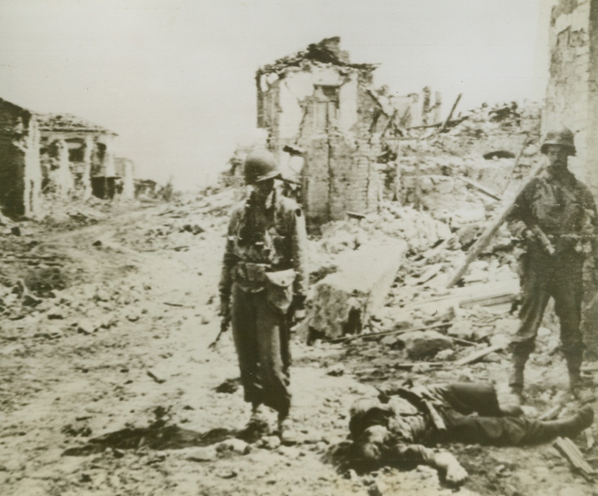 DEATH WITHOUT GLORY, 5/30/1944. CISTERNO, ITALY—This dead German, found by two 5th Army infantrymen in a debris-littered street of Cisterno, gave his life for a hopeless cause. Fighting to the end to hold the Italian key town in the face of Allied assault, he and his comrades finally bowed down and the 5th Army troops took the town. The Allies are now within sight of Rome and smashing into German defenses in the Alban Hills. Credit: US Army Radiotelephoto from Acme;