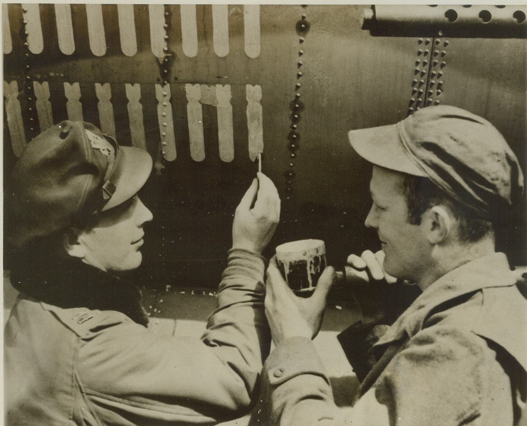 Chalking Up 100th Mission, 5/16/1944. ENGLAND -- Capt. Paul Shannon (left), Attica, Kan., paints 100th bomb symbol on 9th Air Force Marauder medium bomber "Mild and Bitter" at an English base as T/Sgt. William L. Stuart, Donna, Tex., crew chief of the bomber, watches. Stuart has groomed the plane, the first in the E.T.O. to fly 100 missions, for every one of its flights. Credit:-WP-(ACME);