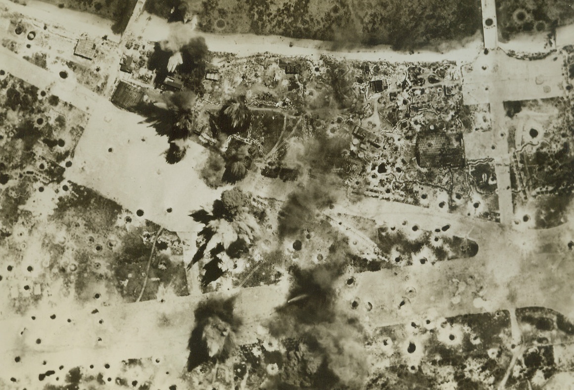 Practice Bombing – The Real Thing, 5/10/1944. Central Pacific – Bombs pock mark an air strip on one of the few remaining Jap bases in the Marshalls, one of the most heavily bombed spots in the world. These islands, not further identified by the Navy, are now being attacked thrice daily as part of a battle indoctrination program for new 7th AAF bomber crews. Credit: USAAF photo from ACME;