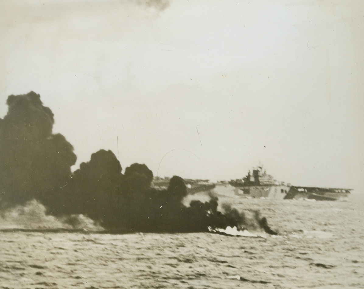 Score One for the Navy, 5/20/1944. Truk – A sheet of flame on the water with dense black smoke rising from it is all that remains of this Japanese torpedo bomber which was met by a hail of anti-aircraft fire when it attempted to hit the Pacific fleet carrier (in the background) during the naval attack on Truk April 29-30, 1944. Credit (US Navy photo from ACME);