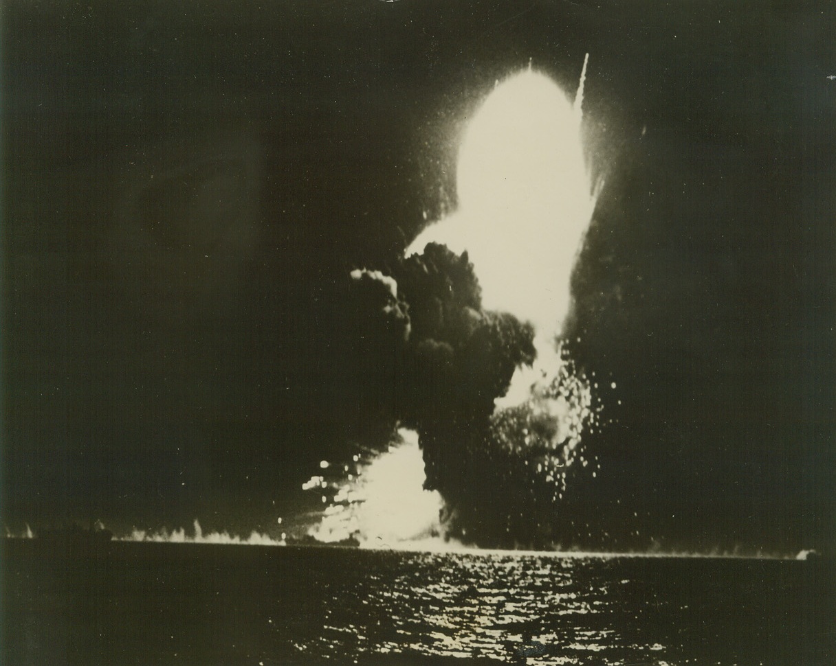 Tower of Destruction, 5/11/1944. North Africa – Cutting into the dense blackness of night, flames and smoke rise hundreds of feet into the air as an allied freighter explodes after a direct hit by a Nazi bomber.  This dramatic photo of war pyrotechnics was taken at the height of a Nazi bomber attack on the North African coast. Credit line (US Coast Guard photo from ACME);