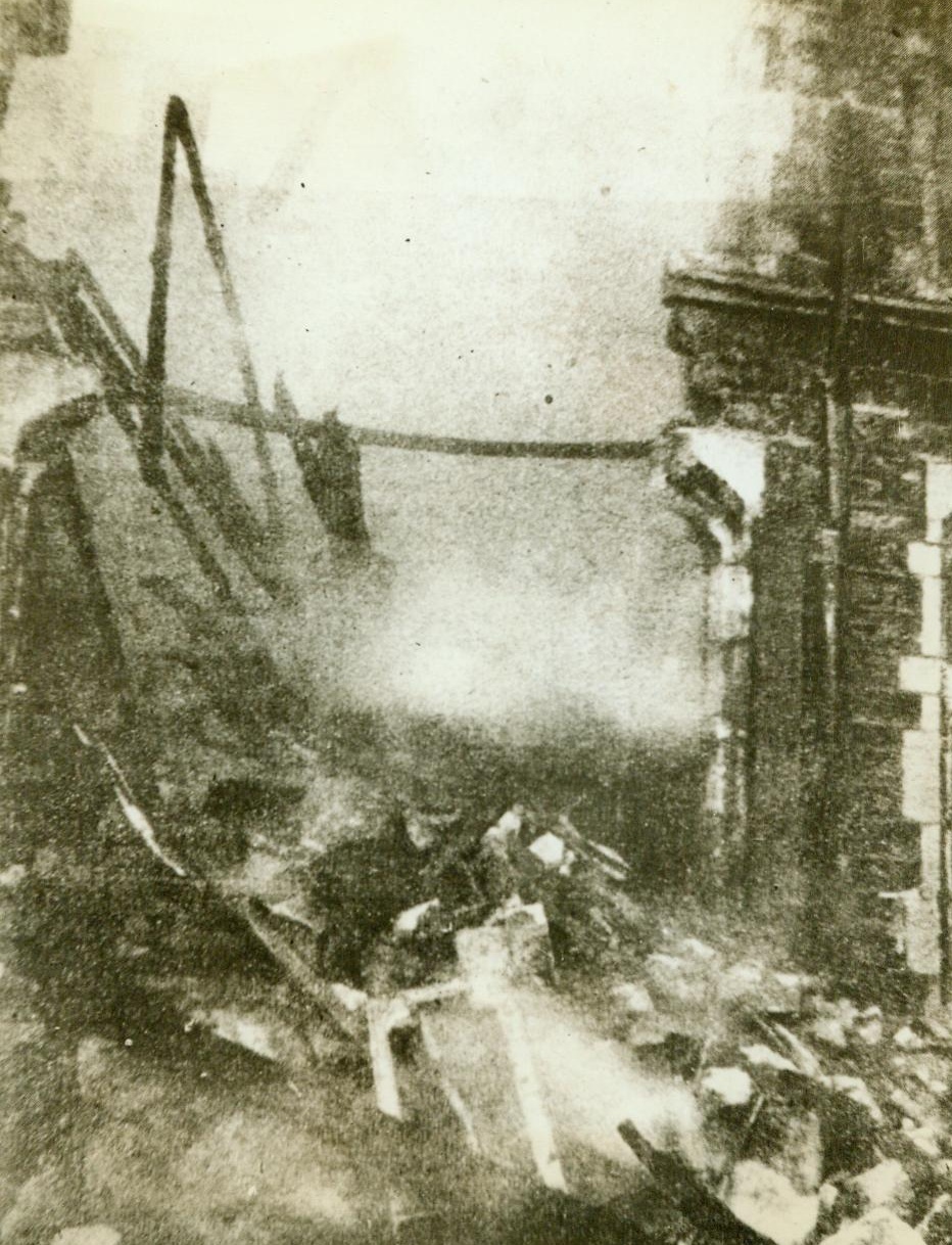 War Sends Its Little Gift Of Roses, 5/19/1944. France - Burning embers fall to the ground from this building on the Channel coast of France, and only small parts of the walls are left standing after the Allies flew over and brought gifts, in the form of blockbusters. The renewed intensity of Allied Air Raids is at last giving the enemy a taste of what their planes have been giving to England for the last two years. Credit: ACME;