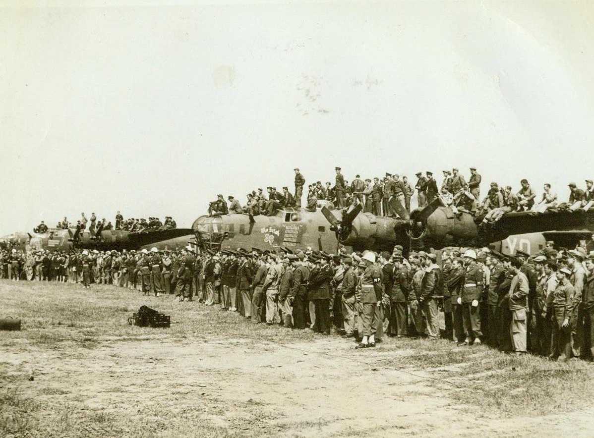 Honor Ploesti Raiders, 5/18/1944. Somewhere in England - The strong wings of Liberators that participated in the first low-level daylight raid on the oil fields of Ploesti make standing room for U.S.A.A.F. fighting men watching ceremonies in which Ploesti raiders were honored. Men who took part in the attack were awarded medals and War Department Citations when Lt. Gen. Carl Spaatz and Lt. Gen. Jimmy Doolittle visited the base of the Liberator Bombardment Group somewhere in England. Credit: ACME;