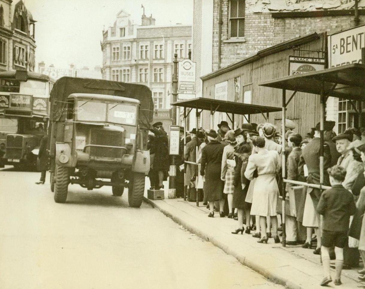 Army Trucks Step In, 5/3/1944. London -- Stranded when London bus drivers went on strike in objection to long working hours recently, these Britishers wait to climb into Royal Army trucks that took over bus routes while grievances were being discussed. Using a mineral water crate as a step, one woman climbs into the truck pinch-hitting for Bus 73.  Credit: ACME;