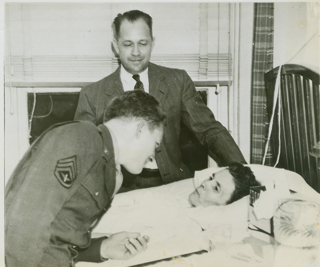 Gunner Flies Home to Mother, 5/6/1944. Poplar Bluff, MO.—Mrs. Mary Pauline Dodd, critically ill in a hospital in Poplar Bluff, MO., greets her son, Staff Sgt. Everett L. Dodd, a tail gunner in a flying fortress, who arrived at her bedside after a 20-hour Atlantic crossing from an American air base in England, where he was given permission to return to the United States because of his mother’s illness. Mr. Dodd, center, looks on as mother and son are reunited. Credit: ACME.;