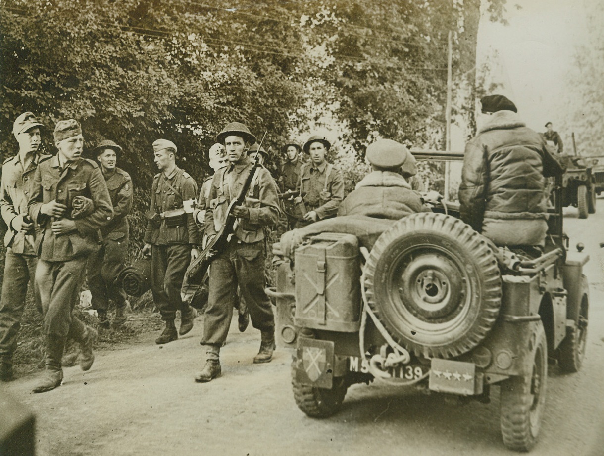 “Achtung—Montgomery”, 6/13/1944. SOMEWHERE IN FRANCE—Awestricken, German prisoners gape at the sight os eneral Sir Bernard Montgomery perched in a Jeep in the first stages of the Allied invasion.  The Nazies are being marched back by British “Tommies” to the Allied beachhead prior to English PW camps.Credit ACME;