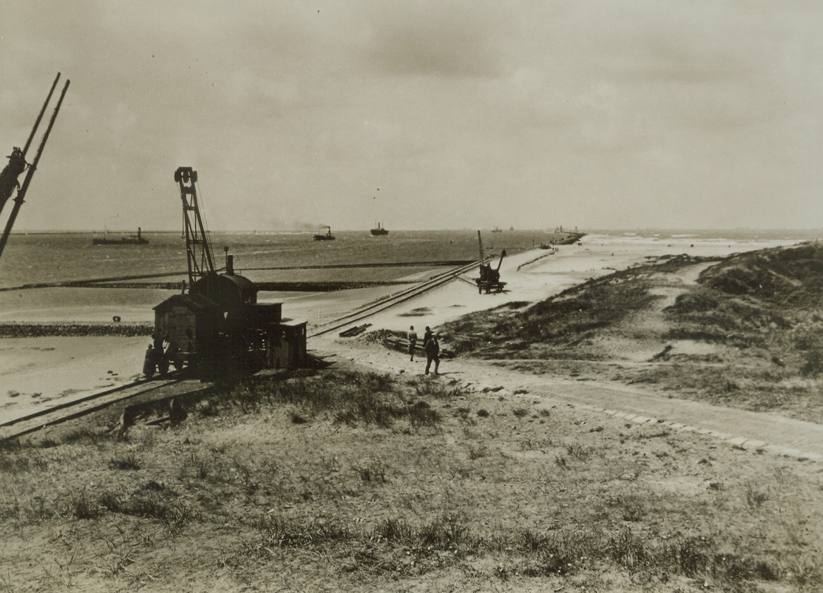 Leave your Homes, 6/5/1944. Broadcasting urgent instructions from the Allied High Command, BBC carried a message to the people of Holland, urging all residents living with 35 kilometers (about 18 miles) of the Dutch Coast to leave their homes immediately and also keep off roads, railways and bridges. Here is a scene at Hook of Holland, a coastal village on the North Sea, at the entrance of the water way that leads to Rotterman. Photo shows the entrance piers to the ocean harbor, the beach and the sand dunes.  Credit: ACME PHOTO FROM NETHERLANDS INFORMATION BUREAU.;