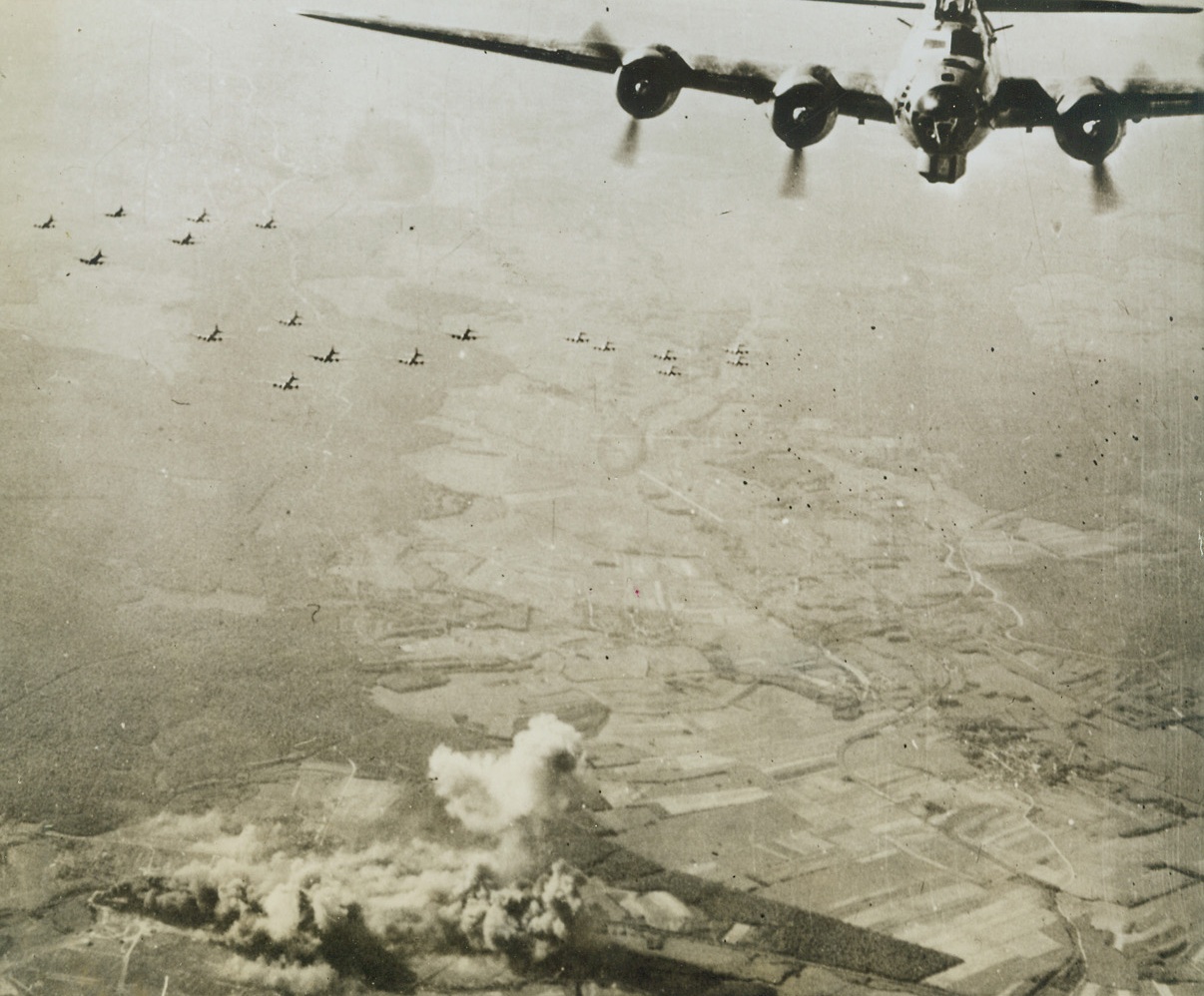 Nazi Airfield Blasted, 6/2/1944. FRANCE—Flying Fortresses of the U.S. Army 8th Air Force head for home, leaving the Nazi airfield at St. Dizier, near Reims, burning. Hits were registered on hangars and fuel storage sheds. Today our air forces continued the pre-invasion pounding of the invasion coast in attacks on Northern France, in Belgium and Holland. Credit: USAAF photo from ACME.;