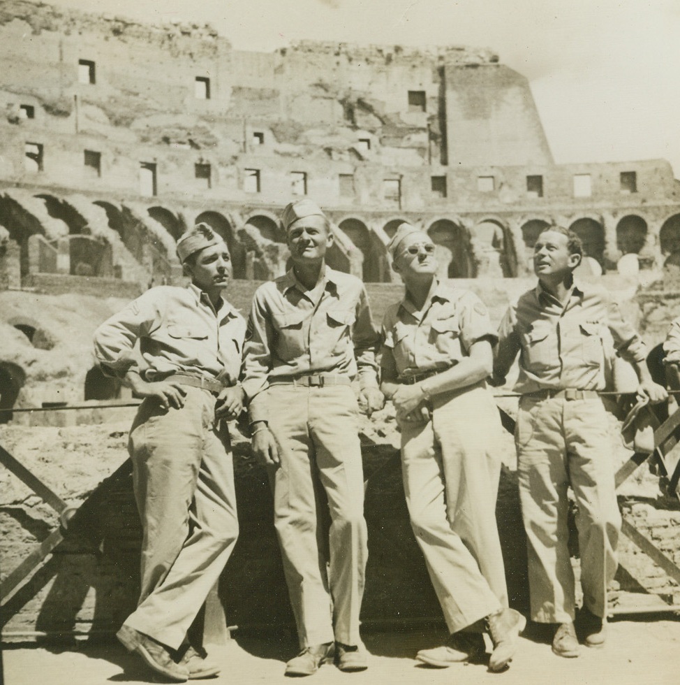 Get a Load of That!, 6/17/1944. ROME, ITALY – Relaxing after the hard fighting which preceded the Allied entry into Rome, these G.I.’s do a little sightseeing. Here they are getting an eyeful of the Coliseum in Rome, relic of the days of Caesar and Cicero. Left to right: Cpl. Randell Herman, Birthright, Tex.; S/Sgt. Marshall Veal, Oconee, Ga.; Pfc. Malcome Lawson, Clairmont, N.H., and Cpl. William D. Shore, Chicago, Ill.  Credit (Acme) (WP);