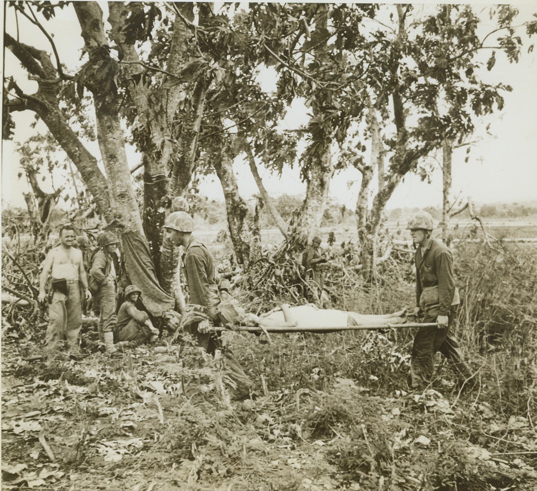 Prepare to Deliver War Baby, 6/28/1944. Saipan – A Marine doctor and corpsman carry a pregnant Jap woman to an aid station where her baby was delivered a few hours later. In carrying the woman to the prison camp station, these two mercy bearers were shot at by Jap snipers and had to wait a half hour in a ditch while Marines exchanged gunfire with the hidden sniper. Credit: ACME;