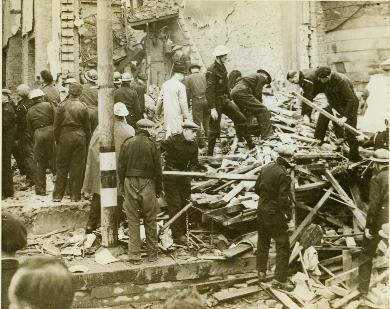 Damage done by pilotless plane, 6/19/1944. SOUTHERN ENGLAND – Rescue workers search the ruins of robot-bombed shops in southern England after an attack by German pilotless planes. It was disclosed today that the Nazi high command intended to send their demon ships into action at four times the strength with which they are attacking. Six months of ceaseless bombing of the pilotless plane launching platforms changed Hitler’s plans. CREDIT LINE (ACME);