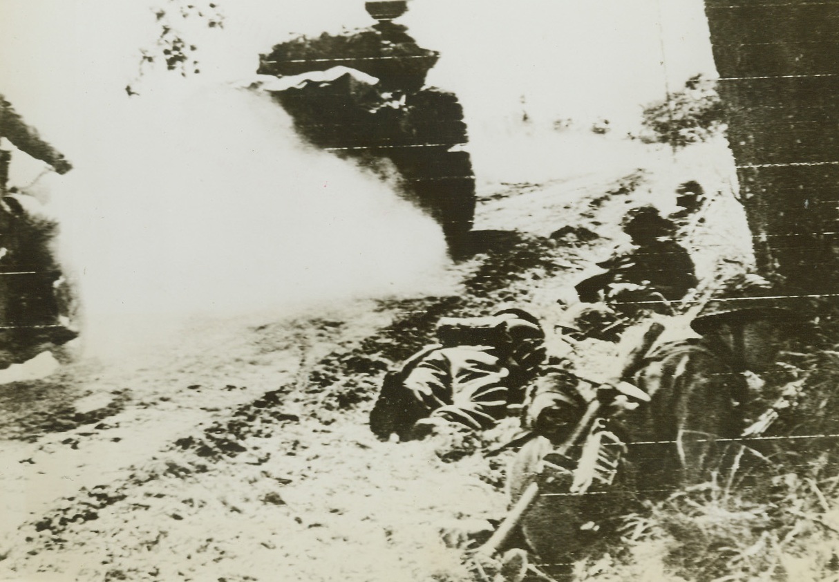 Speeds to Battle, 6/30/1944. France—A Sherman tank followed by a dispatch rider pass British infantrymen using a ditch for shelter while holding positions on a roadside between Tilly and Caen. Headquarters has announced that 60 German tanks have been knocked out in the racing battles around Caen. Credit: US Army radiotelephoto from ACME.;