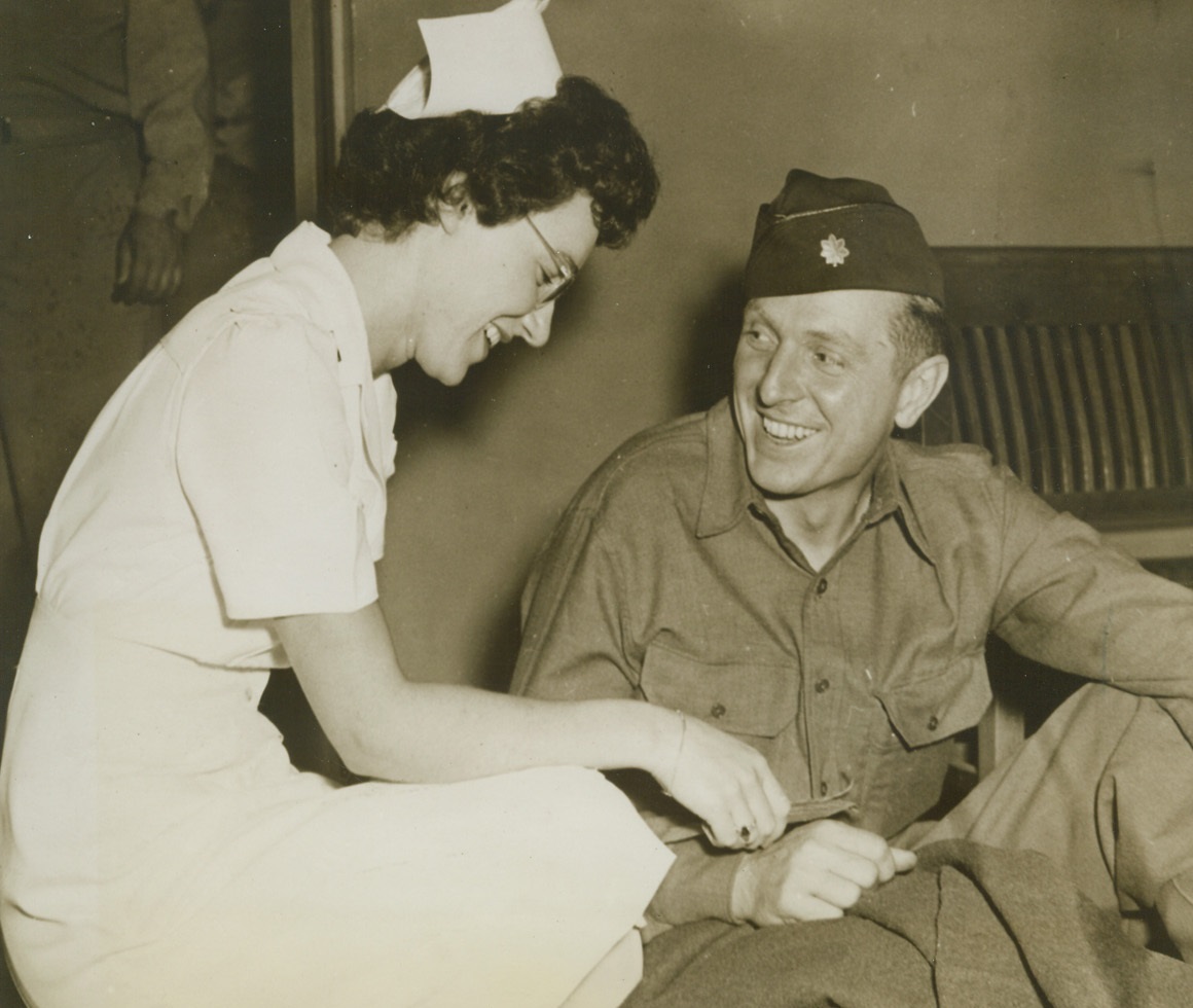 First D-Day Wounded Return to US, 6/25/1944. New York – Lt. Col. Michael C. Murphy grins with genuine happiness at nurse Lt. Olga Williams after his arrival at Mitchel Field last night (June 24) aboard an Air Transport Command Hospital Evacuation Plane. Col. Murphy, a Glider Pilot from Lafayette, Ind., and one enlisted man were the first of the invasion wounded to return to the U.S. Credit: Official USAAF photo from ACME;