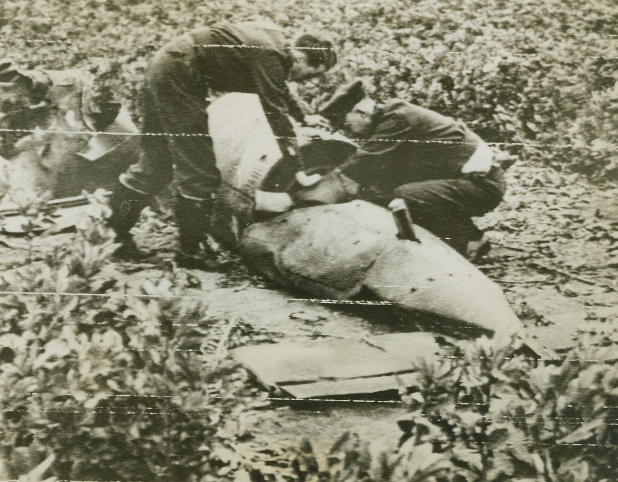 Germany’s Latest, 6/21/1944. England -- British fighter pilots examine a German flying bomb that was shot down in Southern England. Note the tail in the foreground. Credit: British Air Ministry photo from ACME;