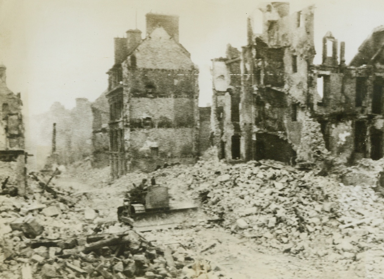 Preparing For Reconstruction in Normandy, 6/22/1944. Valognes, France - Hardly had the smoke of battle cleared, before the U.S. Engineers were busy blasting down dangerous walls, and clearing streets of rubble. Here, an Army bulldozer forces a path through a pile of wreckage in Valognes, near Cherbourg. This demolition is the first step in the reconstruction of these towns liberated by the Allies. Credit: ACME photo via Army Radiotelephoto;