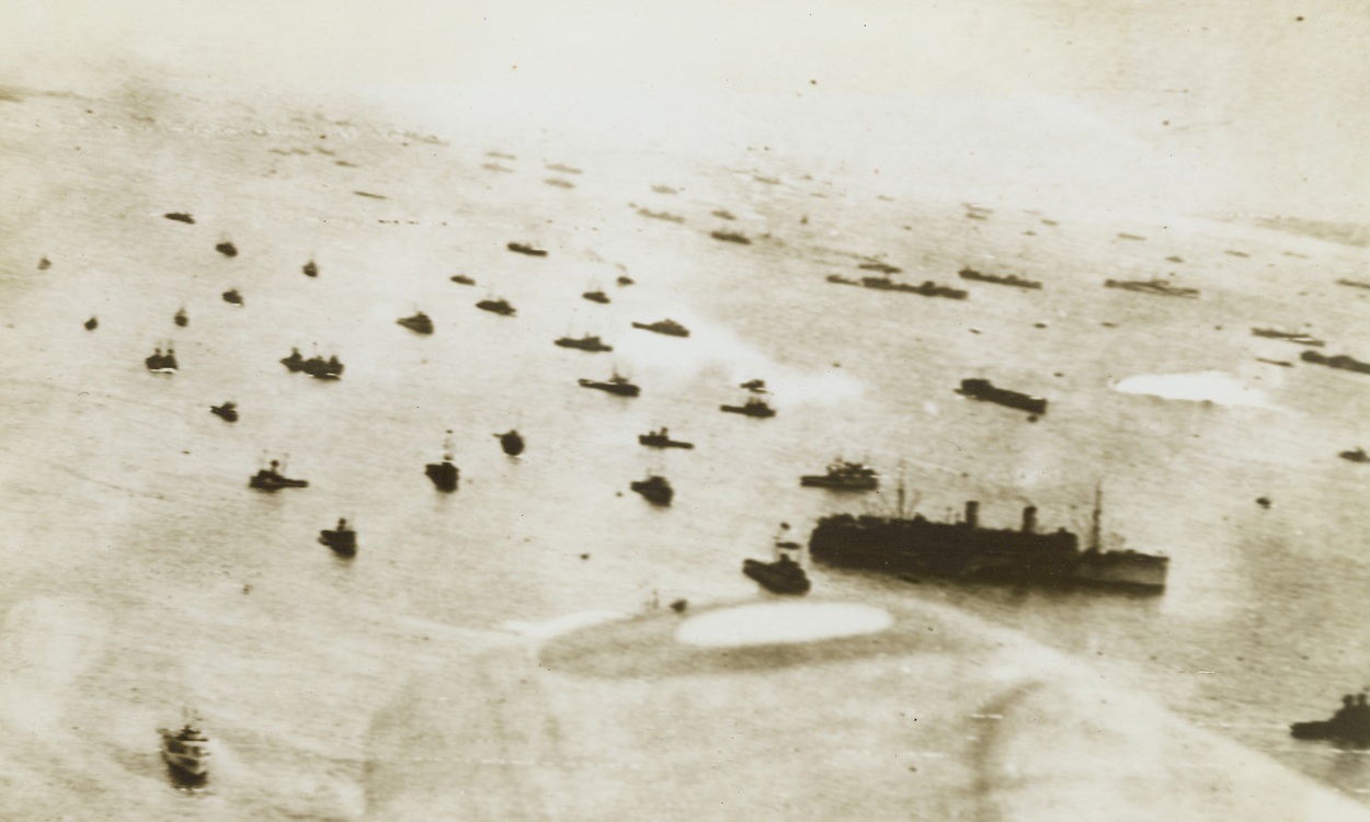 READY FOR THE “JUMP-OFF”, 6/6/1944. ENGLAND—Transports and invasion craft of all types and sizes can be seen in this photo, showing a part of the armada of some 4,000 ships that carried Allied forces to the shores of Normandy. Tonight, British and Americans have penetrated to a point some nine and a half miles inland from the beach. Credit Line (U.S. Signal Corps Radiotelephoto from ACME);