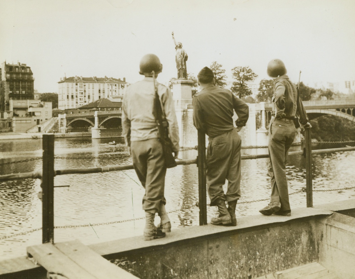 Take Me Back To Noo Yawk!, 6/18/1944. Paris, France - Three American soldiers get their eyes full of the Statue of Liberty which stands in the Seine River, probably seeing in their minds’ eye its counterpart which holds its beacon aloft in New York Harbor. Credit: ACME;