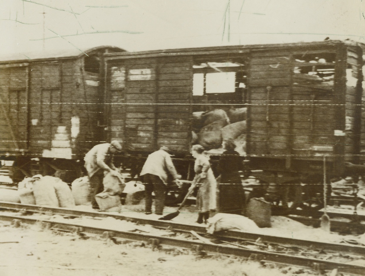 German Supplies Sidetracked, 6/24/1944. France – French farmers salvage grain from freight cars which were bombed by the Allies. The food was en route to Germany when our planes pummeled the train. The French civilians, who were kept in an almost starved condition during the Nazi occupation, are receiving food supplies from their liberations. Credit: Signal Corps Radiotelephoto from ACME;