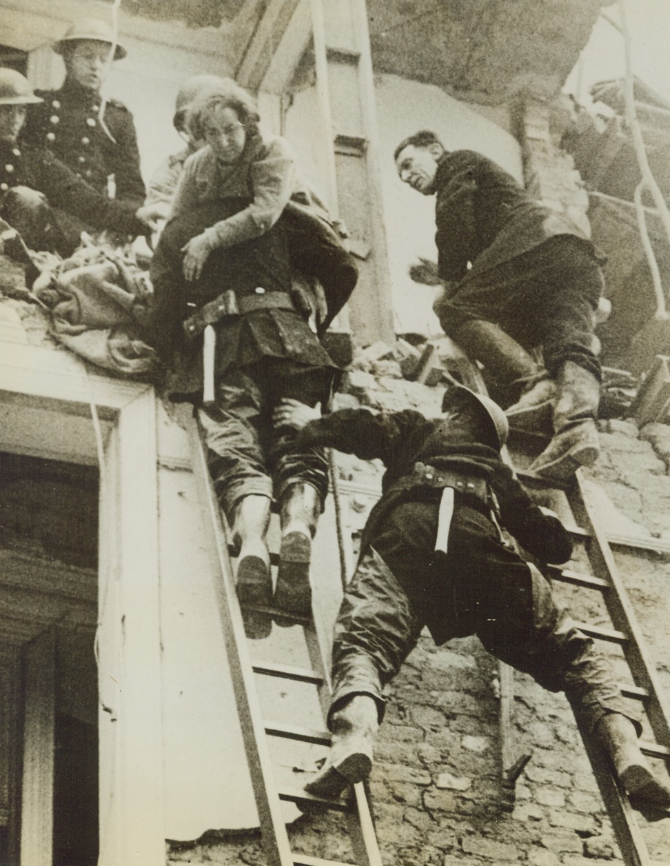 Rescue, 6/28/1944. England – After a pilotless Nazi plane crashed on a house in southern England, its occupants were rescued by firemen and wardens. Here a woman is carried down a ladder from the house. Credit: ACME;
