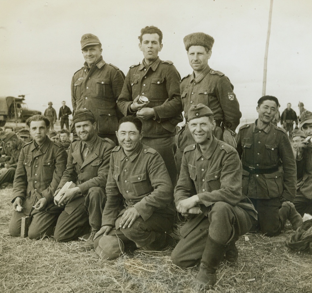 They Fought for Hitler, 6/15/1944. Somewhere in France – Not all of the German Army prisoners taken on the battlefields of France are stalwart, blonde Aryans who were born to rule the world. Not quite so exclusive these days, the “Herrenvolk” is hob-nobbing with men of all races—anyone, as a matter of fact, who can carry a gun for Adolf. Among the prisoners captured in France were: (left to right) front row: a Yugoslav; an Italian; a Turk; a Pole; (back row) a German; a Czech; a Russian who was forced into the army when the Nazis occupied his town; and a Mongol. Credit: Acme photo by Bert Brandt for the War Picture Pool;