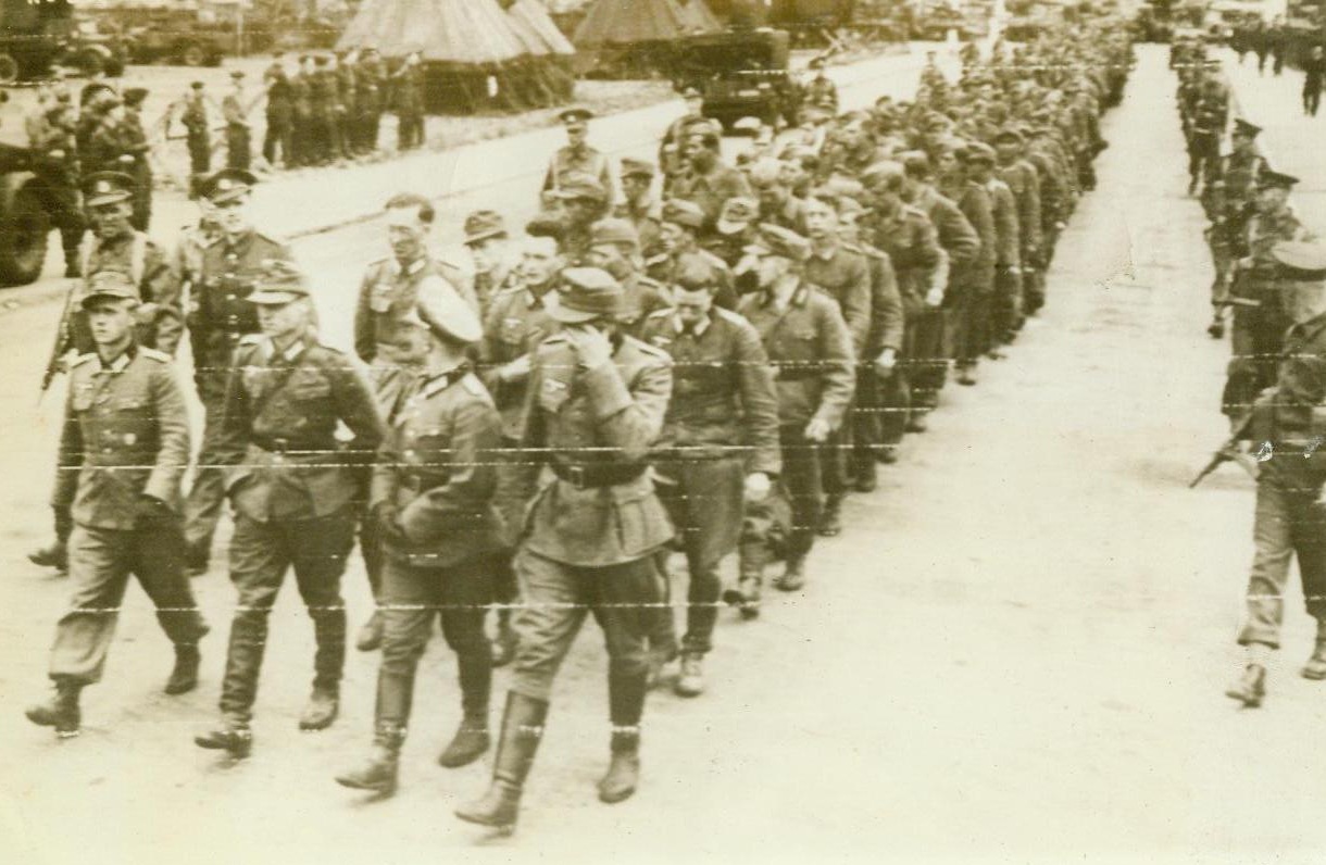 "Invincibles" Finally Reach England, 6/9/1944. England— A long line of once “invincible” German warriors march through an English coastal town on their way to internment camp after their capture on the French beachheads. Press reports state that more than 5,000 prisoners had been taken by the Allies in initial assaults on “Festung Europa.”  6/9/44 Acme RadioPhoto;