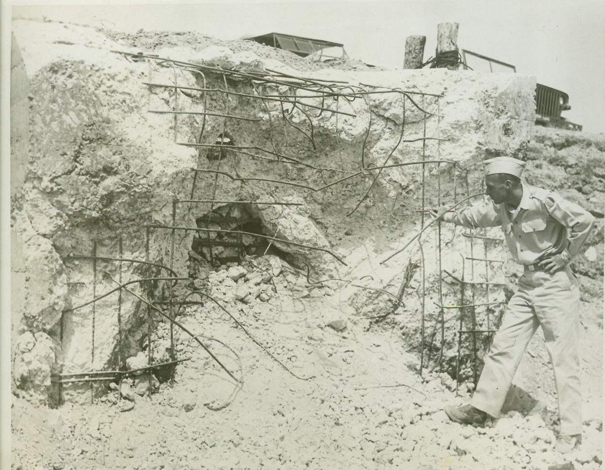 The Infantry School's "West Wall", 6/4/1944. FT. BENNING, GA. -- Newest assault course at Fort Benning is the Infantry School's authentic exterior replica of a section of Germany's famed West Wall, a series of pillboxes and blockhouses, which extends along the coastline from France to Norway and which our invasion troops must reduce from beachheads before they can drive inland to strike at the heart of Nazi-dom. Constructed after study from Allied photographs the course covers 1,000 square yards and is used by the Infantry School in the training of officers and officer candidates. Infantry school demonstration troops, some of whom are shown in these photos, carry out "assaults" for the benefit of each new class. Live ammunition is used and every three weeks the concrete pillboxes and blockhouses must be largely rebuilt and barbed wire torn by bangalore torpedoes must be restrung by engineer troops assigned to the school. PHOTO NO. 4: Maj. H.A. Cornell, Portland, Ore., engineering officer who is an instructor at the Infantry School, inspects a destroyed pillbox on the "West Wall" course. Credit Exclusive ACME Photo;