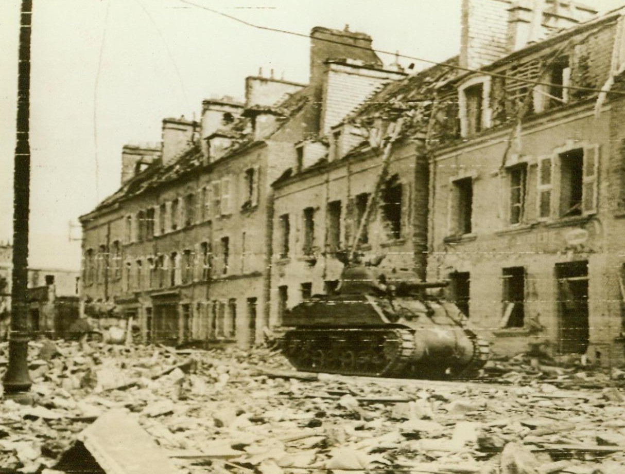 New Meaning For Word "Devastation", 6/28/1944. Cherbourg, France – Subjected to one of the most concentrated land, sea and air bombardments since the battle of Cassino, Italy, Cherbourg today lies in ruins. Its port facilities, however, were of such permanent construction that Army engineers should have them in good shape within a few weeks – with limited usage possible within a few days. Here, (above), an American tank rumbles through a rubble-strewn street as it enters Cherbourg on a “mopping-up” patrol. 6/28/44 (Army Radiotelephoto From ACME);