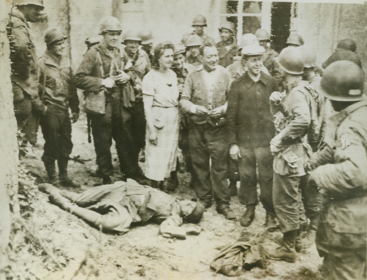 French Strike For Allied Cause, 6/14/1944. France—As the Allies advance through France, the French people, under direct orders from Gen. Eisenhower, are committing acts of sabotage and doing what they can to hinder the Nazi troops trying to stop the Allied armies. A group of French people tell American soldiers about the dead German in foreground who was killed by the Frenchman at right after he was forced to work for the Nazi at $2 a week. Credit: Signal Corps radiotelephoto from ACME;