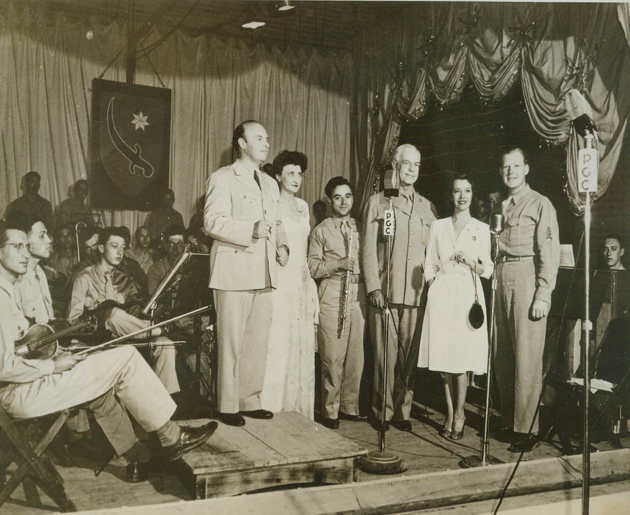 U.S. Stars Give Concert For Troops, 7/27/1944. IRAN—Following a concert given for troops ion the Persian Gulf Command, The visiting artists appear for a curtain bow.  Left to right , standing are:  Andre Kostelanetz, conducting the all-soldier orchestra; Miss Carolyn Gray, NBC pianist; Frank Versaci, Flutist; Maj. Gen. Donald H. Connolly, commanding General Persian Gulf Comand; Lilly Pons, Metropolitan Opera Star; and T/3 Frank P. McDonald, announcer.(Passed by censor)Credit; ACME;
