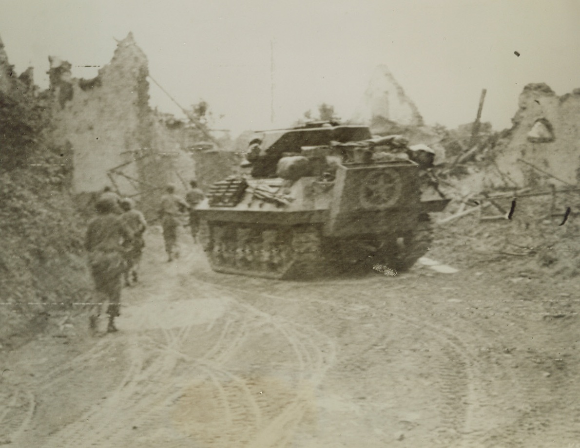 MOVING INTO ST. LO, 7/20/1944. Supported by a tank destroyer, U.S. troops advance through a wreckage-bordered street of the important Normandy town of St. Lo during the final attack that led to the capitulation of rear-guard German forces there. Credit: Acme photo by Andrew Lopez for War Picture Pool;